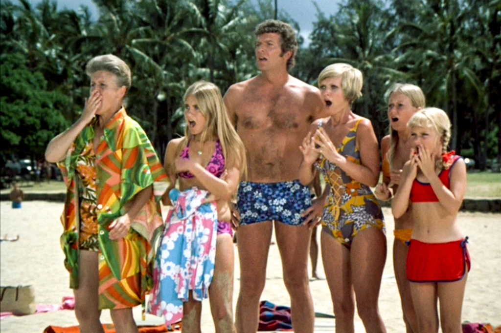 A screen capture of some of the Brady Bunch characters on the beach together.