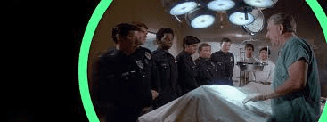 quincy M.E. in the autopsy room with police listening to him lecture